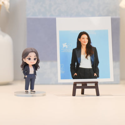Figurine of a woman in a suit next to a photo of a woman on an easel
