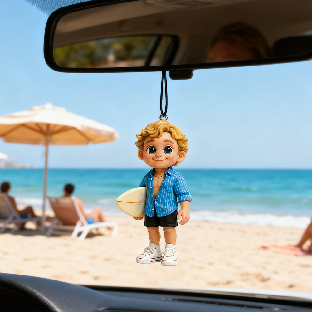 Car air freshener shaped like a boy with a surfboard hanging from a car's rearview mirror with a beach scene in the background.