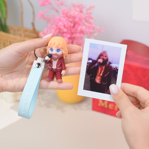 Person holding a keychain with a figurine and a photo of a person with blonde hair.