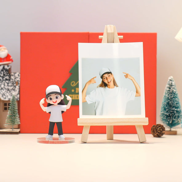 Figurine of a person with a hat next to a photo on an easel against a red background with Christmas decorations.