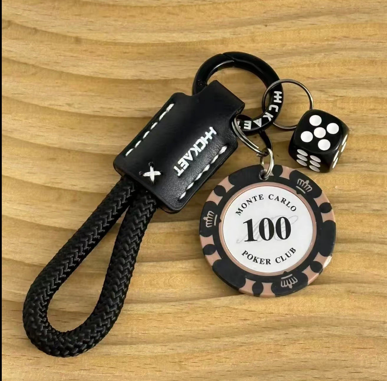 Keychain with poker chip design, dice, and black strap on a wooden surface