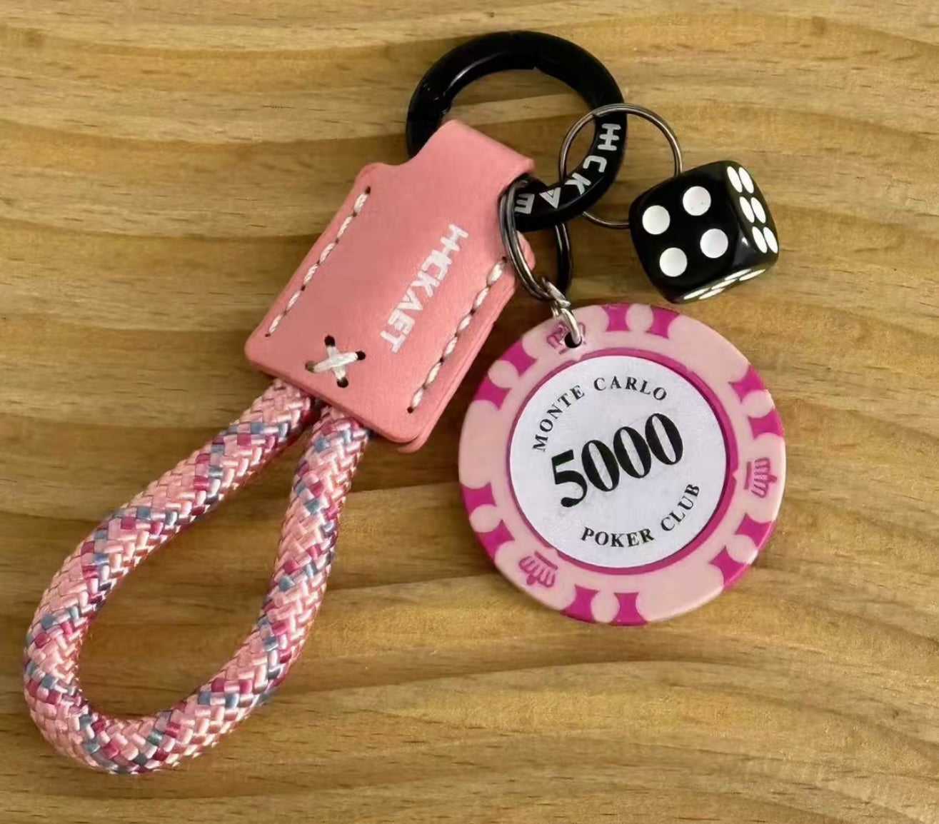 Pink keychain with poker chip and dice on a wooden surface